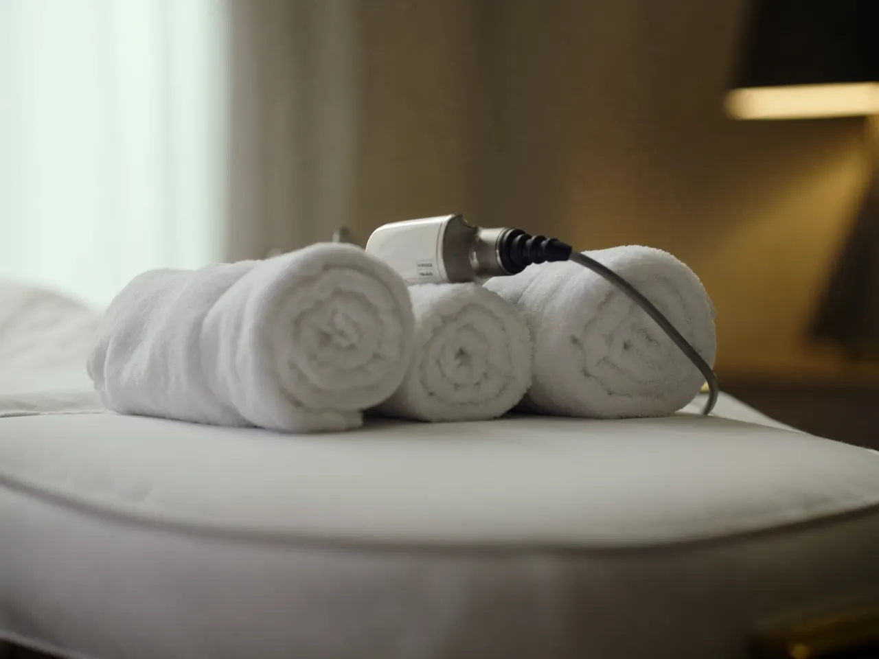 Radiofrequency body contouring handpiece and rolled towels on a treatment bed